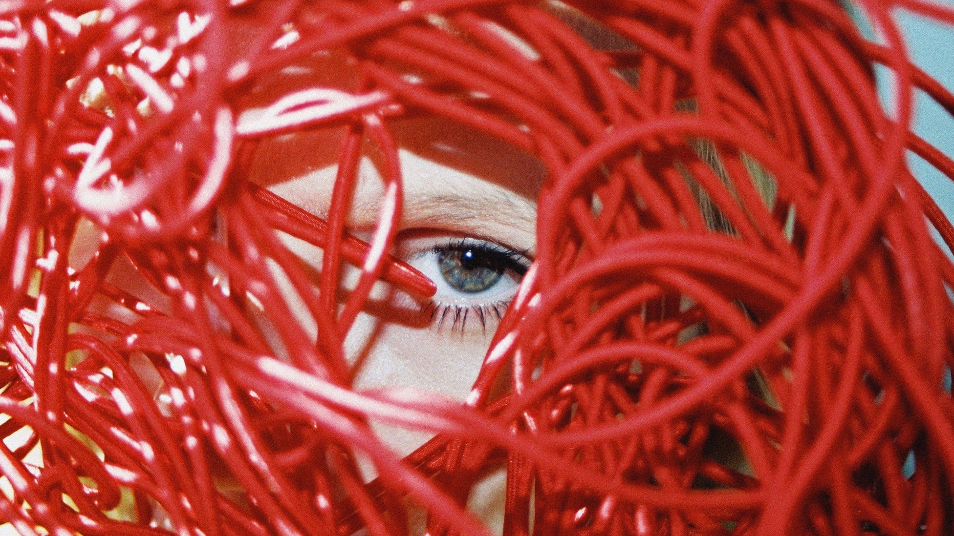 eyeball focused on the viewer through tangled red cords